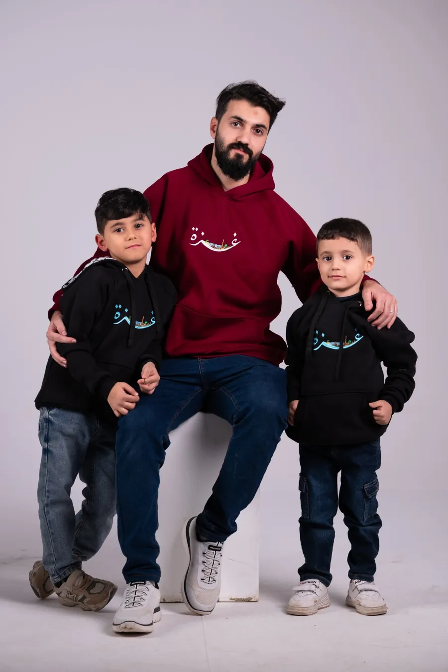 أب وطفلين لابسين هودي غزة